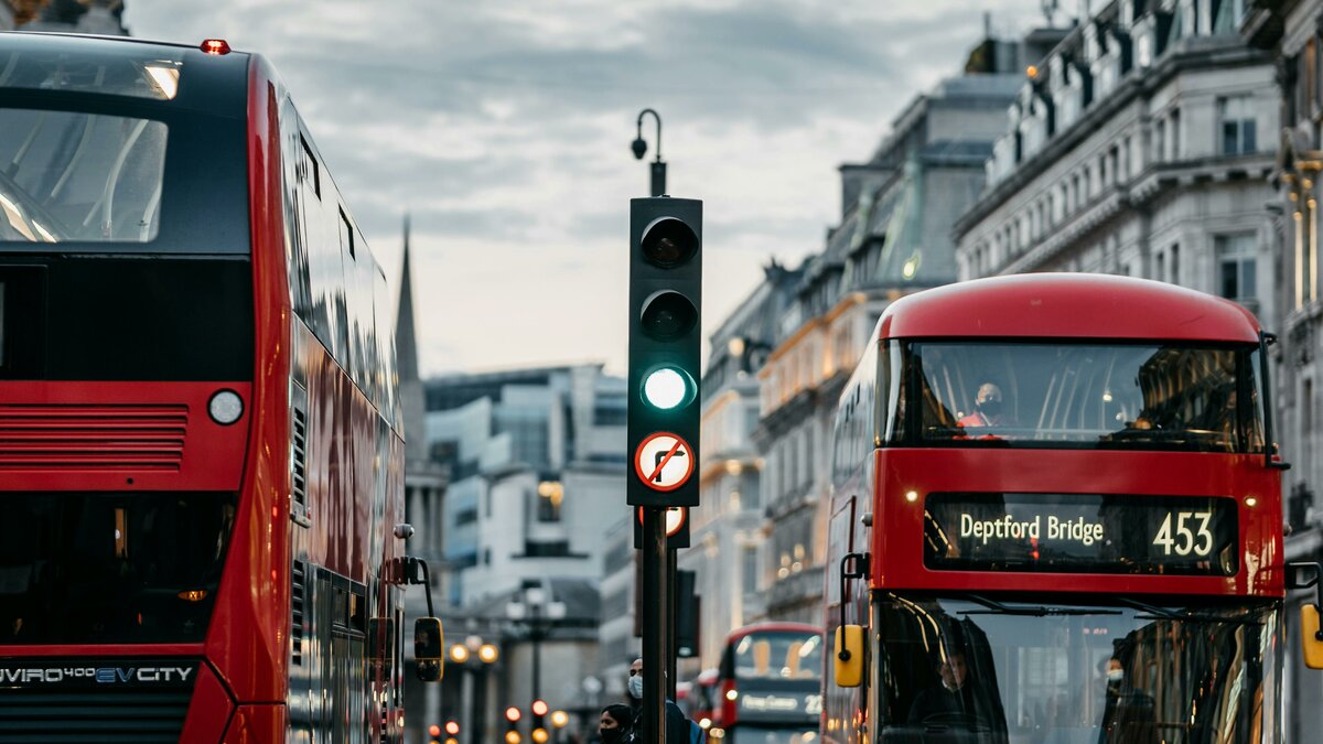 Zwei rote Doppeldeckerbusse nebeneinander vor grüner Ampel | © Pexels