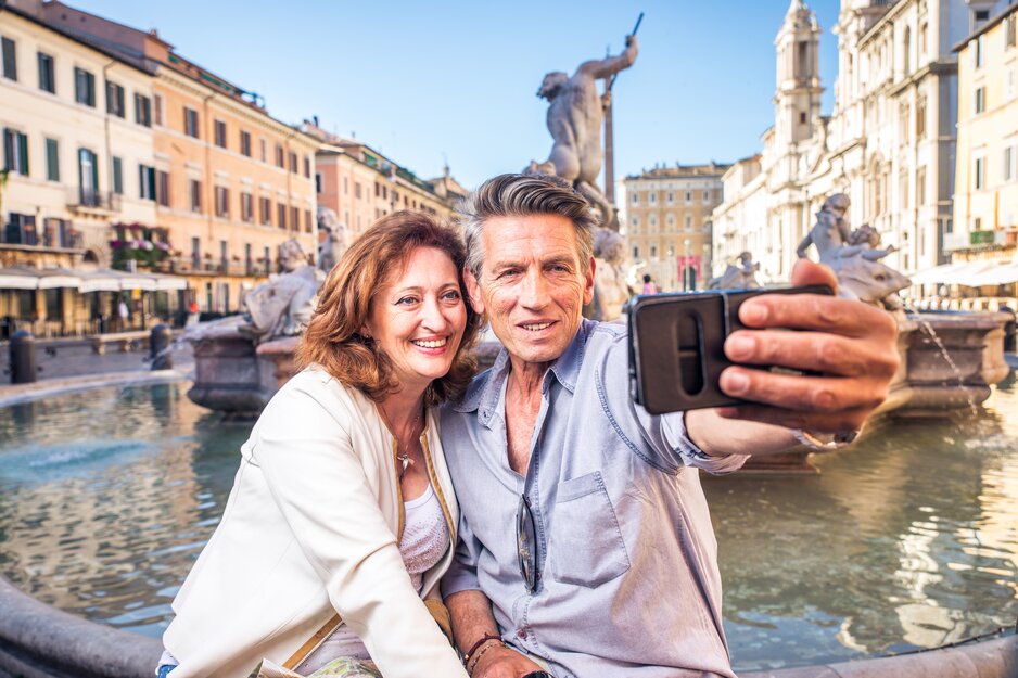 Seniorenpaar vor Brunnen beim Aufnehmen eines Selfies | © Envato Elements