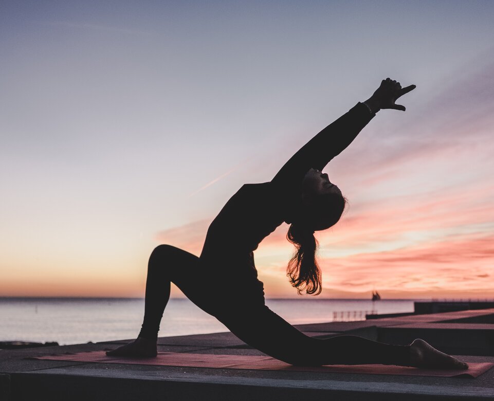 Silhouette einer Frau bei Yogaübungen am Strand | © Photo by <a href="https://unsplash.com/@kikekiks?utm_source=unsplash&utm_medium=referral&utm_content=creditCopyText">kike vega</a> on <a href="https://unsplash.com/?utm_source=unsplash&utm_medium=referral&utm_content=creditCopyText">Unsplash</a>   