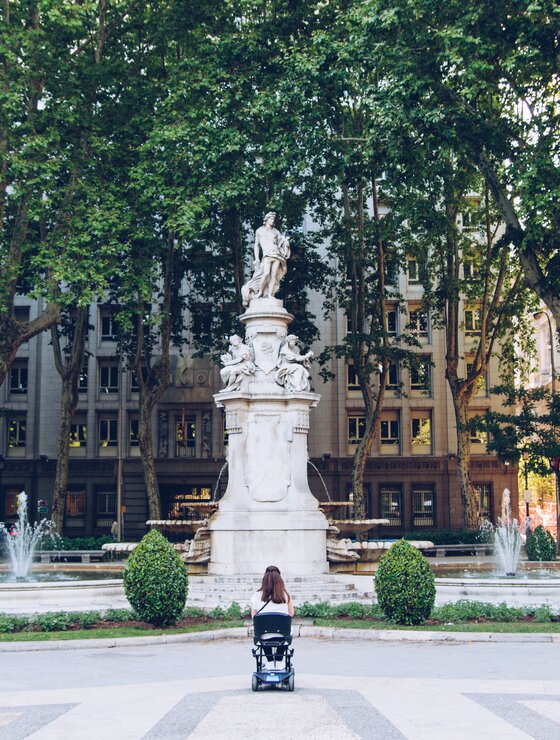 Frau im Rollstuhl vor Brunnen mit Statue | © Carlos Navas Unsplash