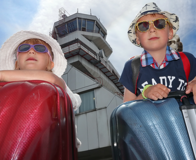 Geschwisterpaar mit Koffer, Sonnenbrille und Hut vor Tower | © Linz Airport