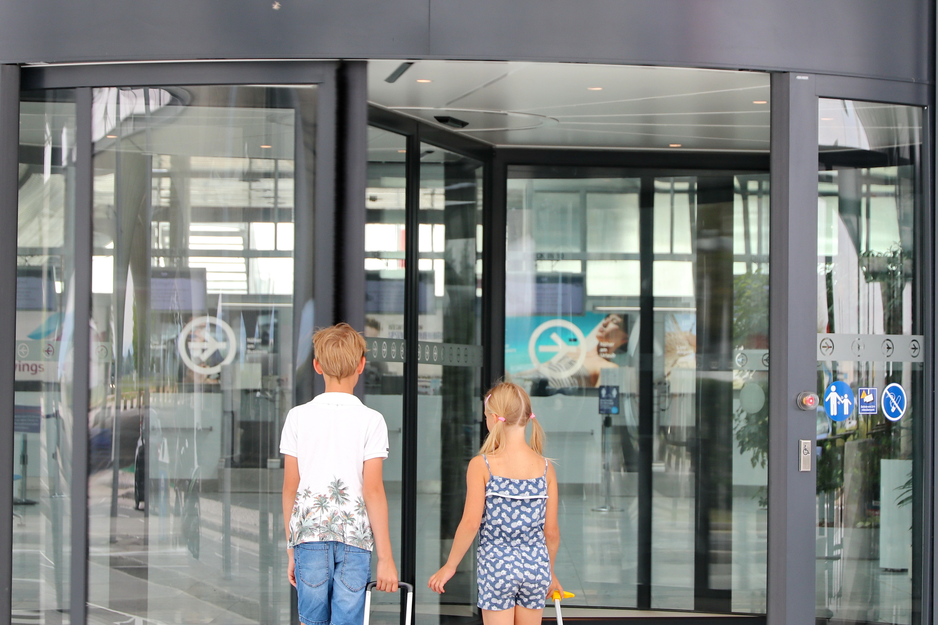 Geschwisterpaar mit bunten Rollkoffern beim Betreten der Abflughalle | © Linz Airport