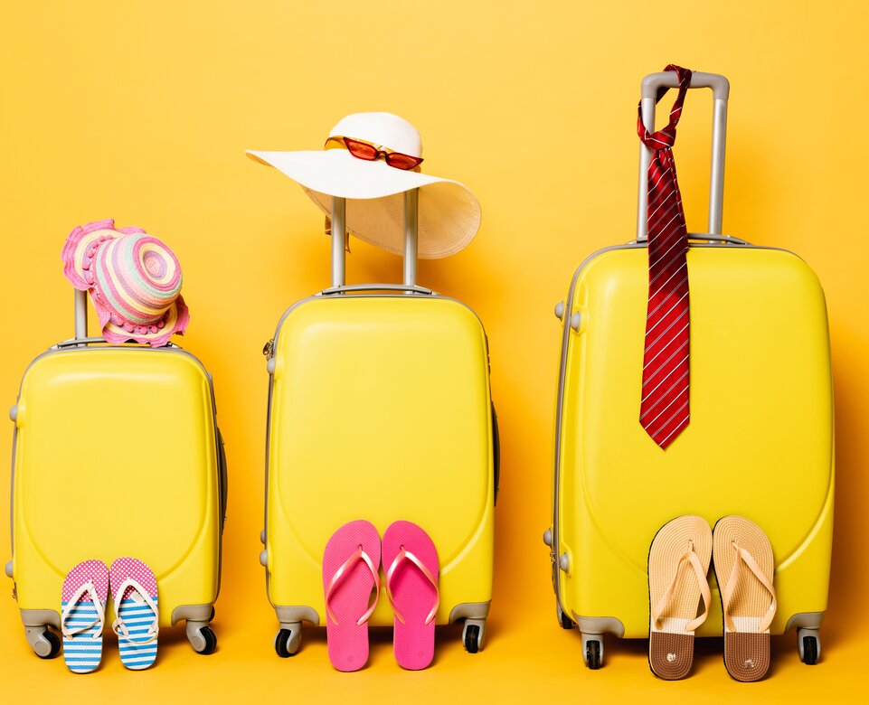 Gelbes Kofferset mit Accessoires vor gelben Hintergrund | © Envato