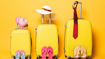 Gelbes Kofferset mit Accessoires vor gelben Hintergrund | © Envato