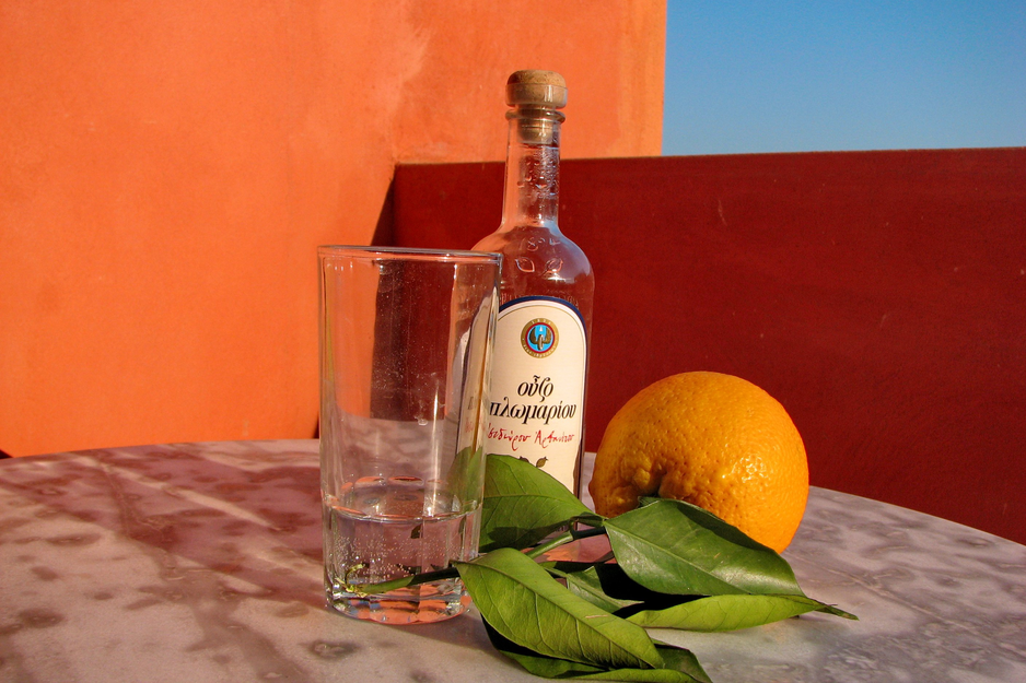 Ouzo-Flasche mit Orange vor orangem Hintergrund | © Linz Airport