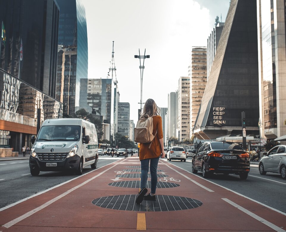 Junge Frau mit Rucksack wandert durch die City | © Guilherme Stecanella Unsplash