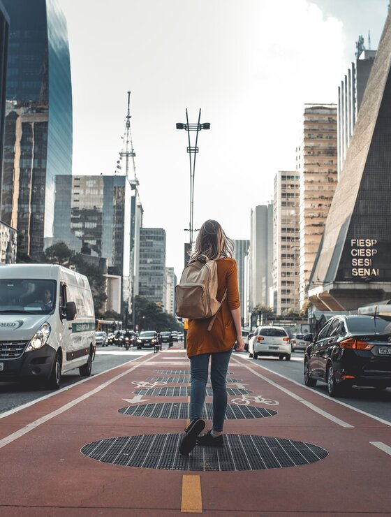 Junge Frau mit Rucksack wandert durch die City | © Guilherme Stecanella Unsplash