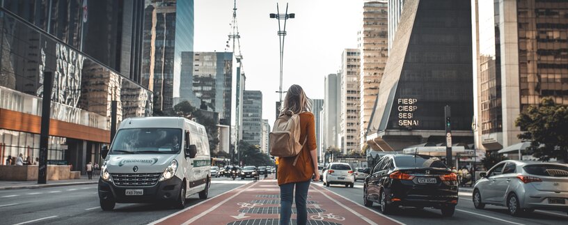 Junge Frau mit Rucksack wandert durch die City | © Guilherme Stecanella Unsplash