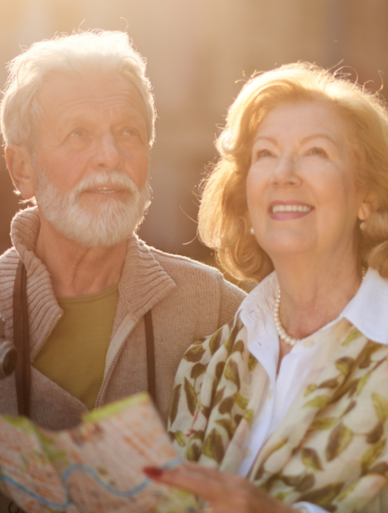 Älteres Paar mit Kamera und Stadtführer lächelt glücklich im Sonnenschein | © Canvas