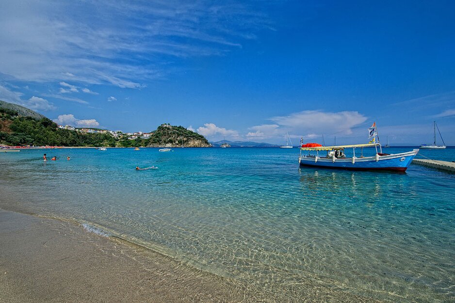 Sandstrand mit kristallklarem Wasser und einem kleinen Boot, das ankert  | © Rhomberg Reisen